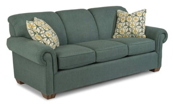 A green couch with two pillows on top of it.