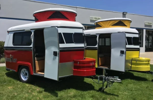 A couple of small trailers parked in the grass.