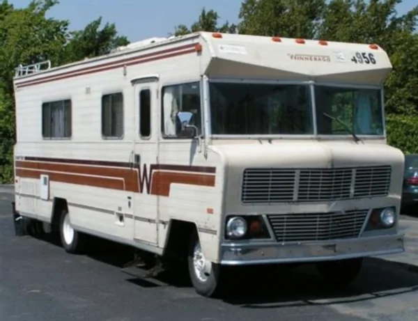 A white and red rv parked in the street.