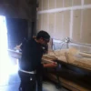 A man in black shirt working on wooden structure.