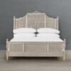 A bed with white sheets and headboard in front of a wall.