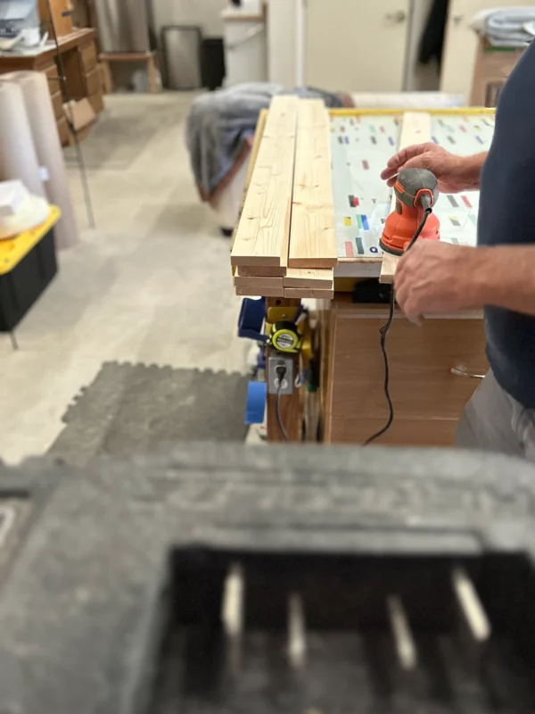 A man is using an electric drill to build a table.