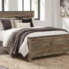 A bed with brown blanket and pillows on it.