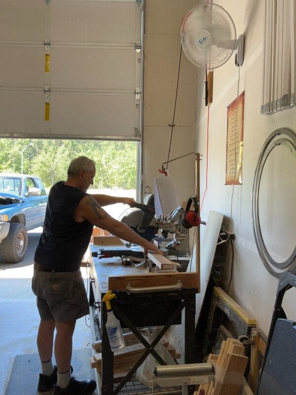 Man using a miter saw in a workshop.